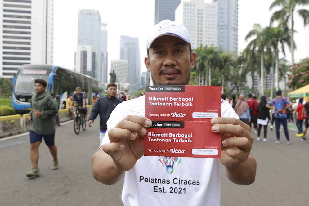 Seorang warga menunjukkan hadian voucher nonton Piala Dunia 2022 di Vidio saat Car Free Day (CFD) di kawasan Sudirman, Jakarta, Minggu (06/11/2022). (c) Nexify/M iqbal Ichsan