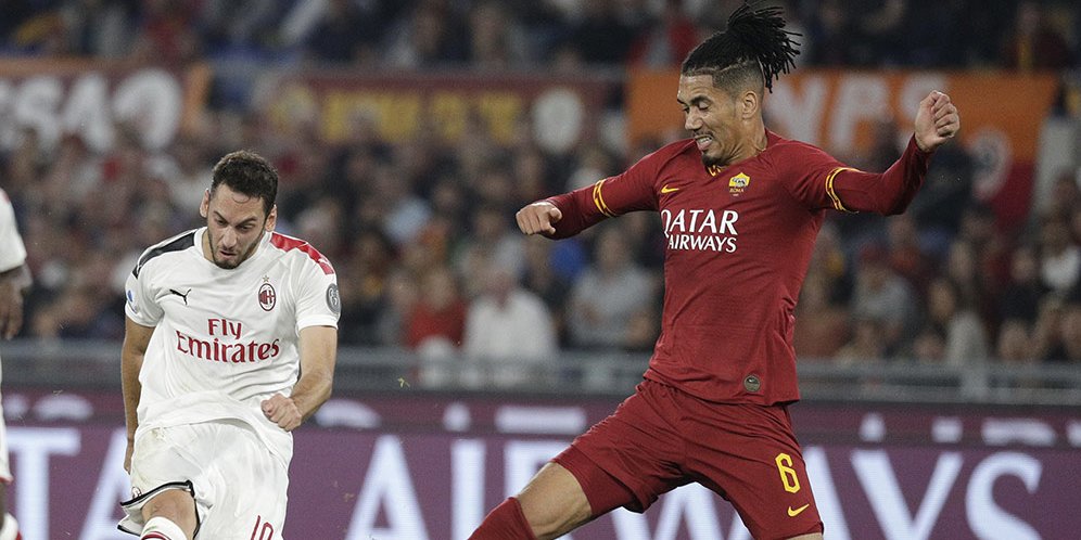 Bek AS Roma, Chris Smalling, berupaya memblokade tembakan dari pemain AC Milan, Hakan Calhanoglu. (c) AP Photo